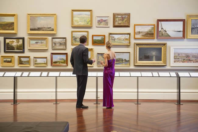 Caucasian couple in evening wear admiring art in museum